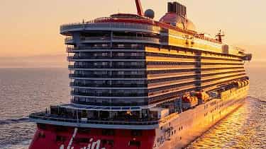 A large cruise ship sails on the ocean at sunset - Scarlet Lady, Virgin Voyages