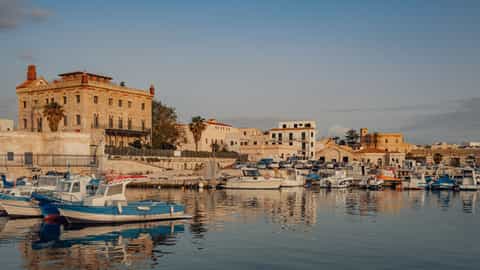 Brindisi, Italy — Beautiful harbor scene in Favignana, Sicily with boats and historic buildings.