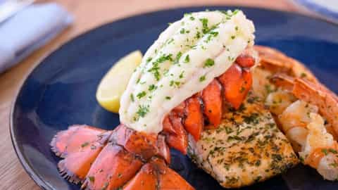 A plate of lobster, fish, and shrimp with lemon - Utopia Of The Seas, Royal Caribbean