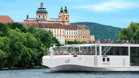A white river ship passes a large monastery - Viking Alruna, Viking River Cruises