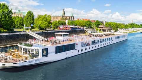 A white river ship sails on blue water near a city - Viking Beyla, Viking River Cruises