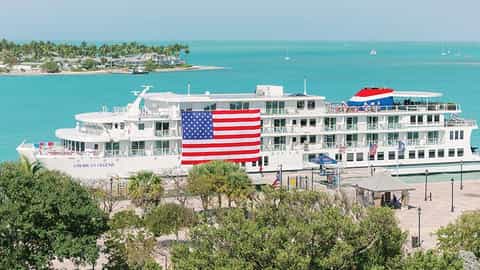 A cruise ship is docked near a tropical island - ACL American Legend, American Cruise Lines