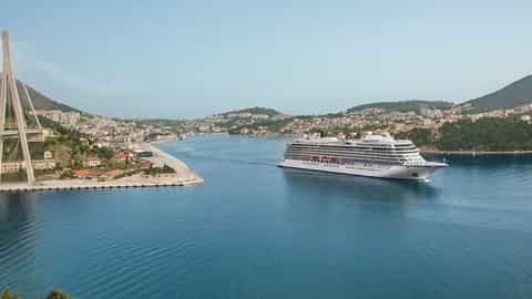 A large cruise ship sails into a coastal city harbor - Viking Jupiter, Viking Cruises
