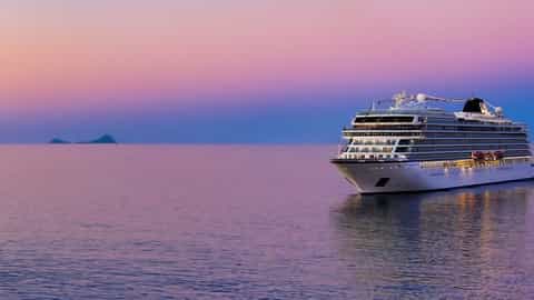 A large cruise ship sails on calm water at sunset - Viking Libra, Viking Cruises
