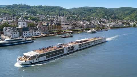 A river ship cruises past a European town on a sunny day - Viking Mani, Viking River Cruises