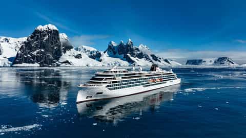 A cruise ship sails through icy waters near snow-capped mountains - Viking Octantis, Viking Cruises
