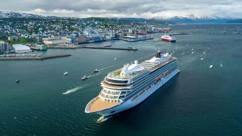 A large cruise ship sails near a coastal city - Viking Sky, Viking Cruises