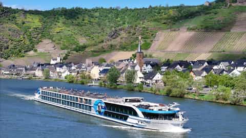 A river ship cruises past a village nestled in a valley - VIVA Moments, Viva Cruises