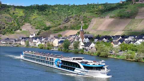 A river ship cruises past a village with vineyards on the hills - VIVA Moments, Viva Cruises