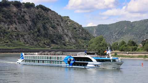 A river cruise ship sails past a steep, tree-covered mountainside - VIVA Tiara, Viva Cruises