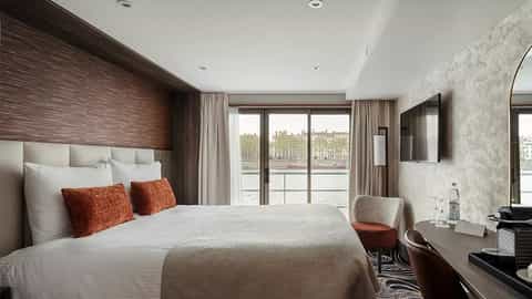 A river view suite bedroom with a large bed and window - VIVA Voyage, Viva Cruises