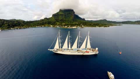 A large sailing ship sails on the ocean near a tropical island - Wind Spirit, Windstar Cruises