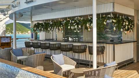 An outdoor bar with seating and a view of the water - Wind Surf, Windstar Cruises