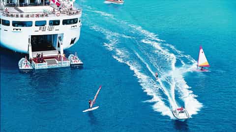 Ship with people on deck and water sports in the ocean - Wind Surf, Windstar Cruises