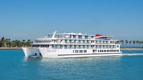 A white cruise ship sails on blue water - ACL American Liberty, American Cruise Lines