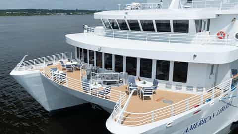 A white ship with outdoor seating areas on its decks - ACL American Liberty, American Cruise Lines