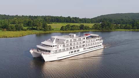 A white riverboat sails on a calm river - ACL American Liberty, American Cruise Lines