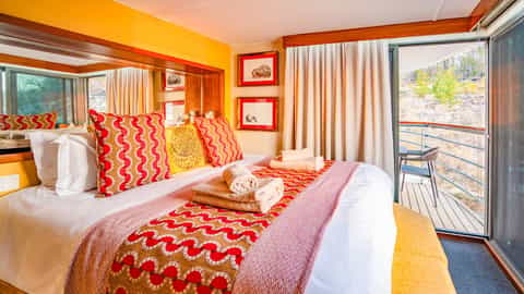A colorful suite bedroom with a balcony view - Zimbabwean Dream, CroisiEurope