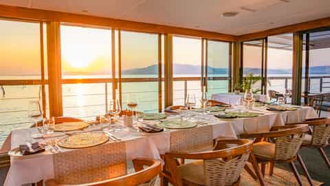 A set dining table with a sunset view over the water - Zimbabwean Dream, CroisiEurope