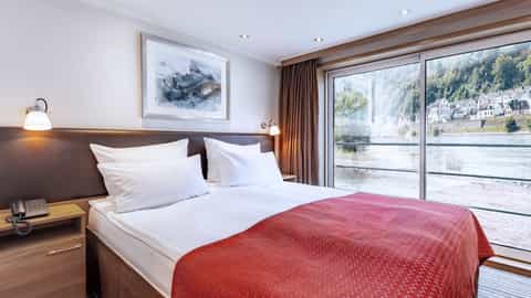 A river view suite bedroom with a large window - Arosa Alea, A Rosa Cruises