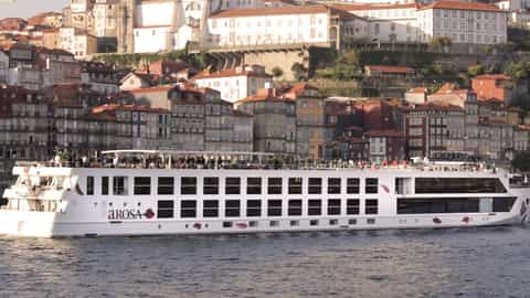A river ship sails past a city on a hill - Arosa Alva, A Rosa Cruises