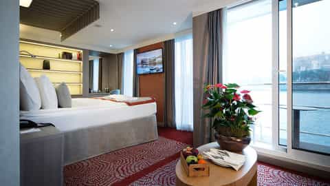A river view suite with a bed and a balcony door - Arosa Alva, A Rosa Cruises