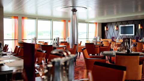 A dining room with tables, chairs, and large windows - Arosa Aqua, A Rosa Cruises
