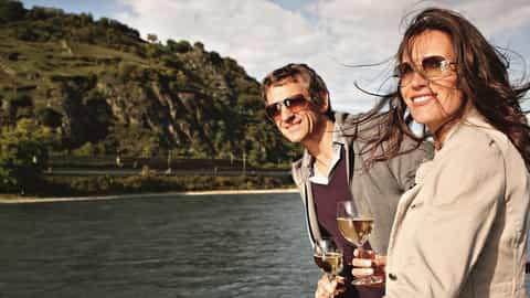 A couple enjoys wine on a river cruise with scenic hills - Arosa Brava, A Rosa Cruises