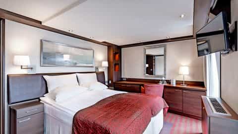 A well-appointed cabin with a bed and seating area - Arosa Clea, A Rosa Cruises