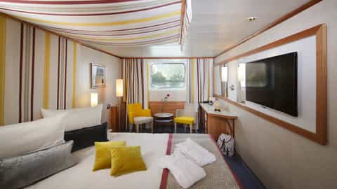 A river cruise cabin with a bed, seating area, and window - Arosa Donna, A Rosa Cruises