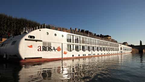 A white river ship sails on calm water - Arosa Luna, A Rosa Cruises