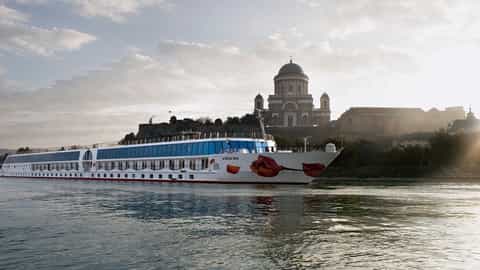 A river ship sails past a historic European city - Arosa Mia, A Rosa Cruises