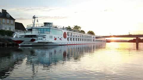 A river cruise ship sails on the water at sunset - Arosa Viva, A Rosa Cruises