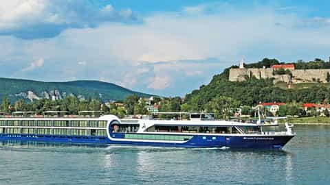 A river ship sails past a historic European town and landmark - Avalon Illumination, Avalon Waterways