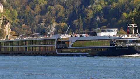 A river cruise ship sails past a forested hillside - Avalon Passion, Avalon Waterways