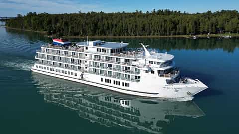 A white cruise ship sails on blue water - ACL American Patriot, American Cruise Lines