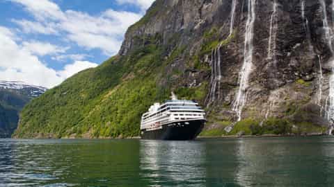 A cruise ship sails past waterfalls in a fjord - Azamara Journey, Azamara Cruises