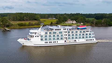 A river cruise ship sails on a calm waterway - ACL American Ranger, American Cruise Lines