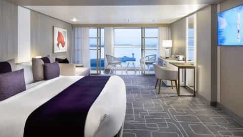 A modern suite with a bed, seating area, and balcony - Celebrity Apex, Celebrity Cruises