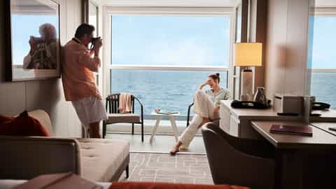 A couple relaxes on a balcony overlooking the sea - Celebrity Ascent, Celebrity Cruises