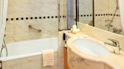 A marble-clad bathroom with a bathtub and sink - Celebrity Constellation, Celebrity Cruises