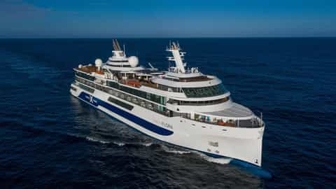 A white cruise ship sails on a deep blue ocean - Celebrity Flora, Celebrity Cruises