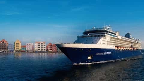 A large cruise ship sails past colorful buildings - Celebrity Summit, Celebrity Cruises