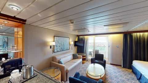 A suite living area with a sofa, chairs, and a balcony view - Adventure Of The Seas, Royal Caribbean
