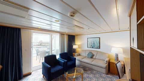 A suite living area with a sofa, chairs, and balcony access - Adventure Of The Seas, Royal Caribbean