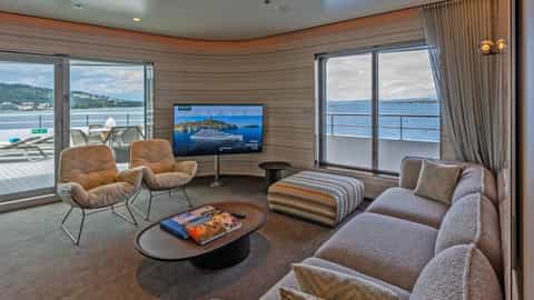 A suite living area with a balcony and ocean view - Emerald Kaia, Emerald Cruises