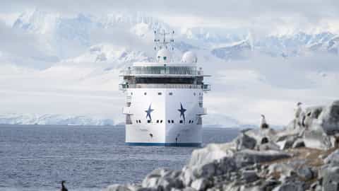 A white ship sails in front of snow-covered mountains - Greg Mortimer, Aurora Expeditions