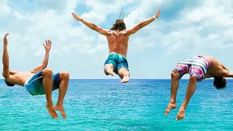 Three people jump into the ocean with ships in the background - Icon Of The Seas, Royal Caribbean