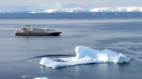 A ship sails past icebergs in Antarctica - Le Boreal, Ponant Cruises