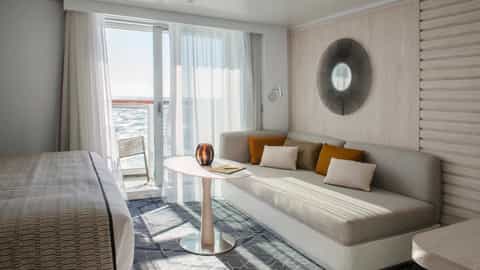 A suite with a bed, sofa, and balcony overlooking the ocean - Le Bougainville, Ponant Cruises